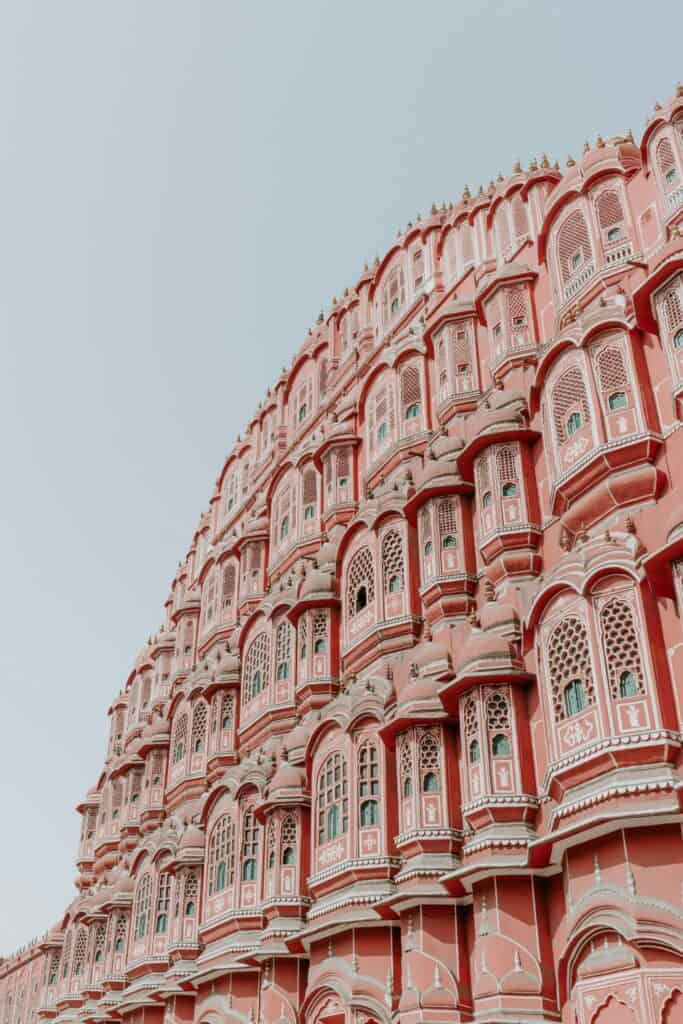 pink facade including windows of the Hawa Mahal pink palace in Jaipur India against a grey sky