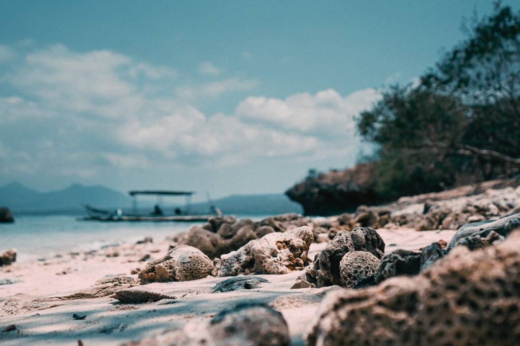 rocky beach on Menjangan Island in Bali, Indonesia, with a small boat anchored near the shore