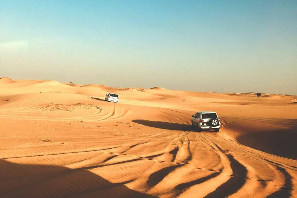 two jeeps driving through the golden sands of the abu dhabi desert