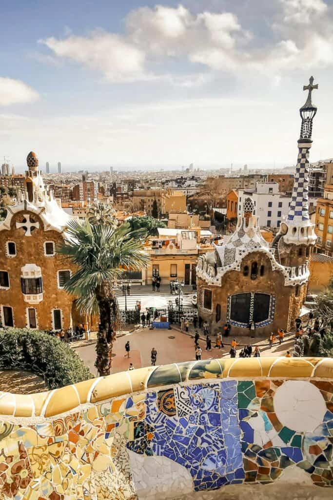 whimsical brown buildings with white roofs and chimneys with intricately designed wall in park guell barcelona spain