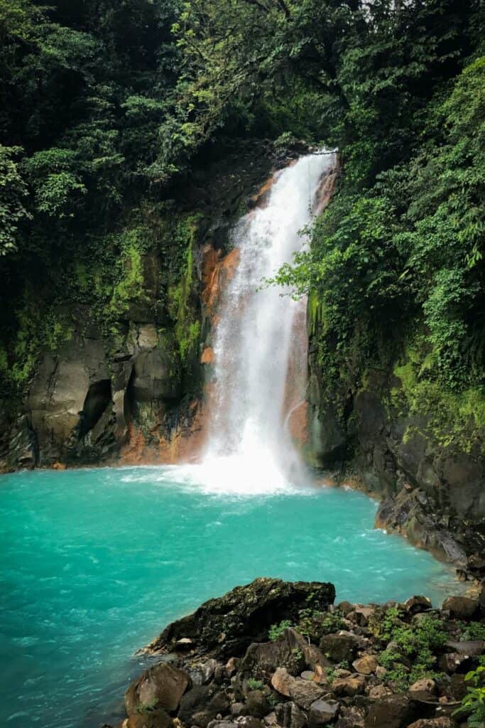 cascading rush of water into a blue pool of the rio celeste waterfall in costa rica